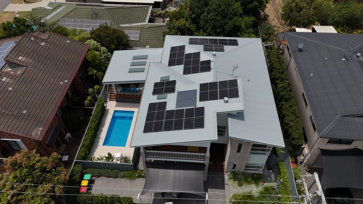 Aerial view of a home with rooftop solar and a swimming pool