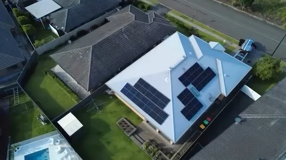 Aerial view of solar panels installed on a blue-roofed home